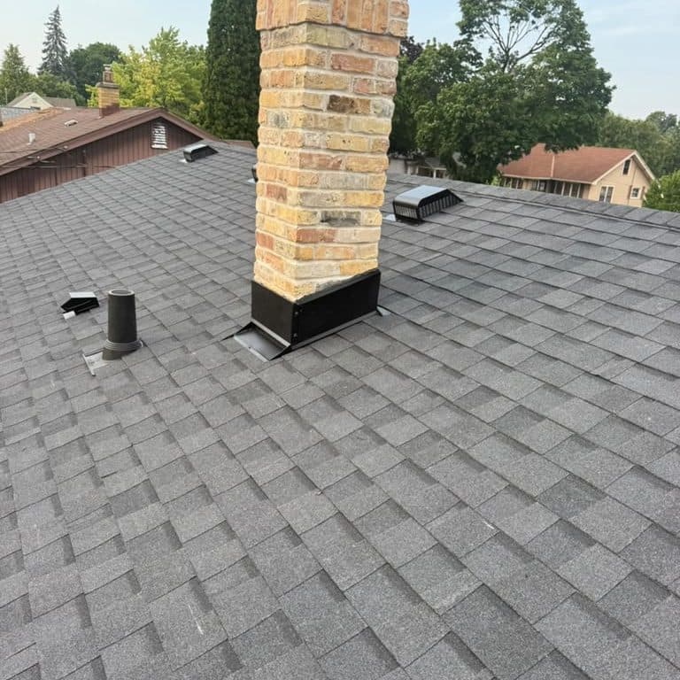Cream brick chimney rebuilt with new dark metal flashing at the roofline